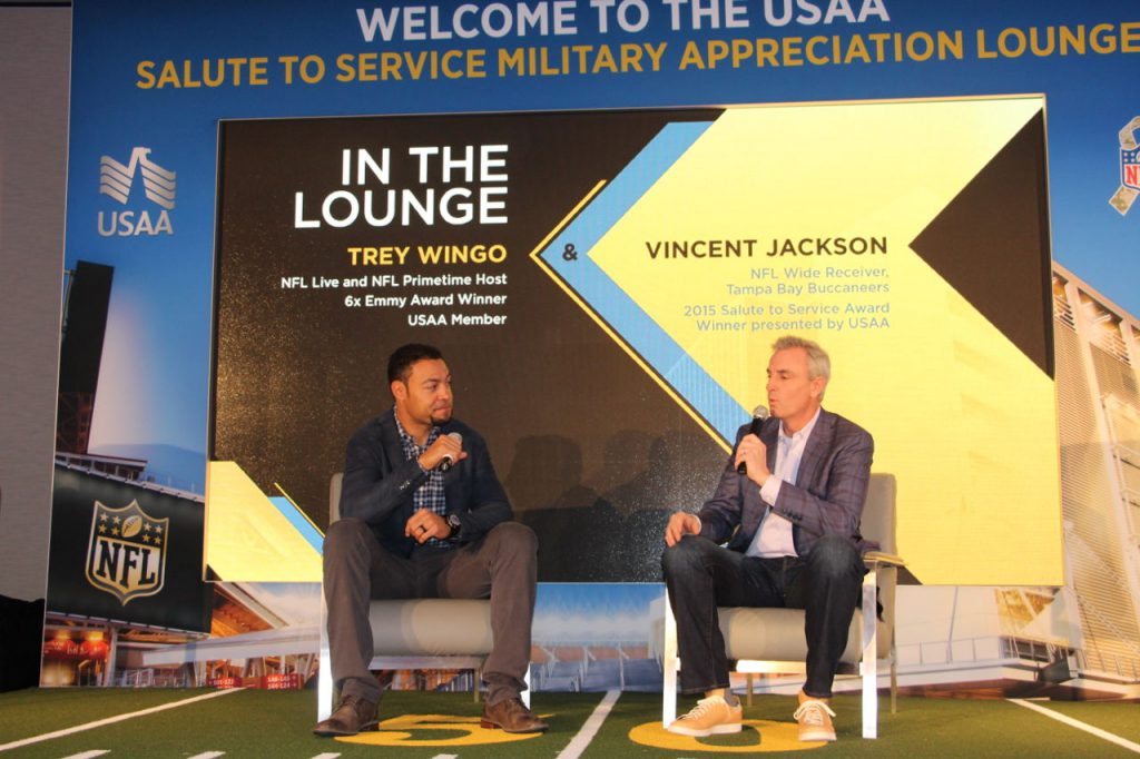 modular wall used as a stage background with 2 men sitting in chairs in front of it holding microphones